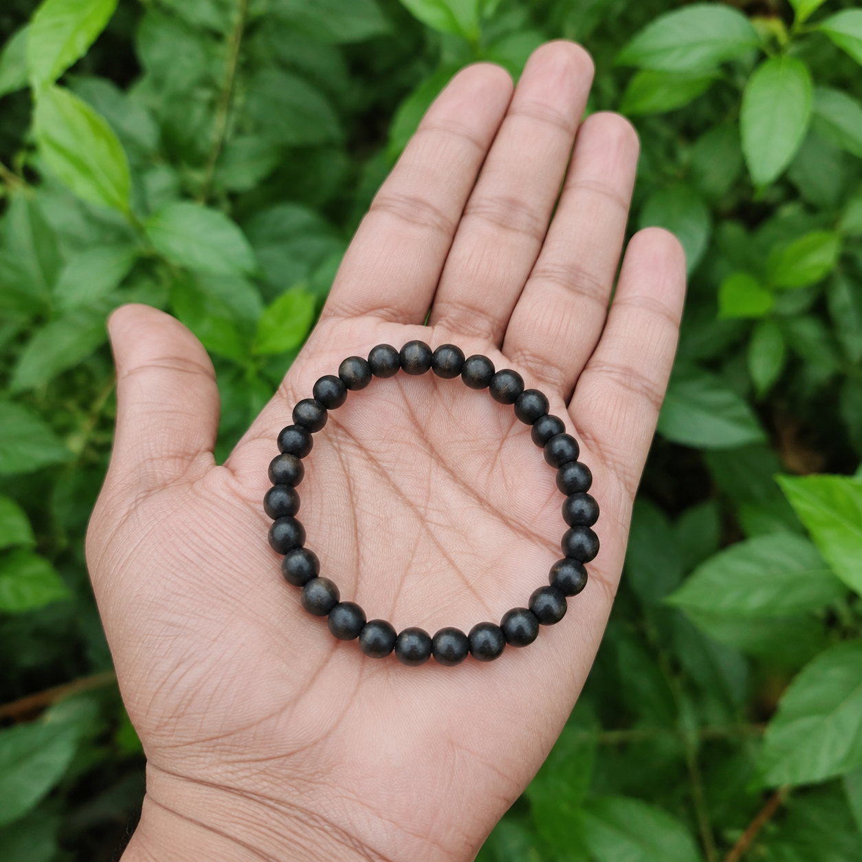 Plain Karungali bracelet held in hand outdoors