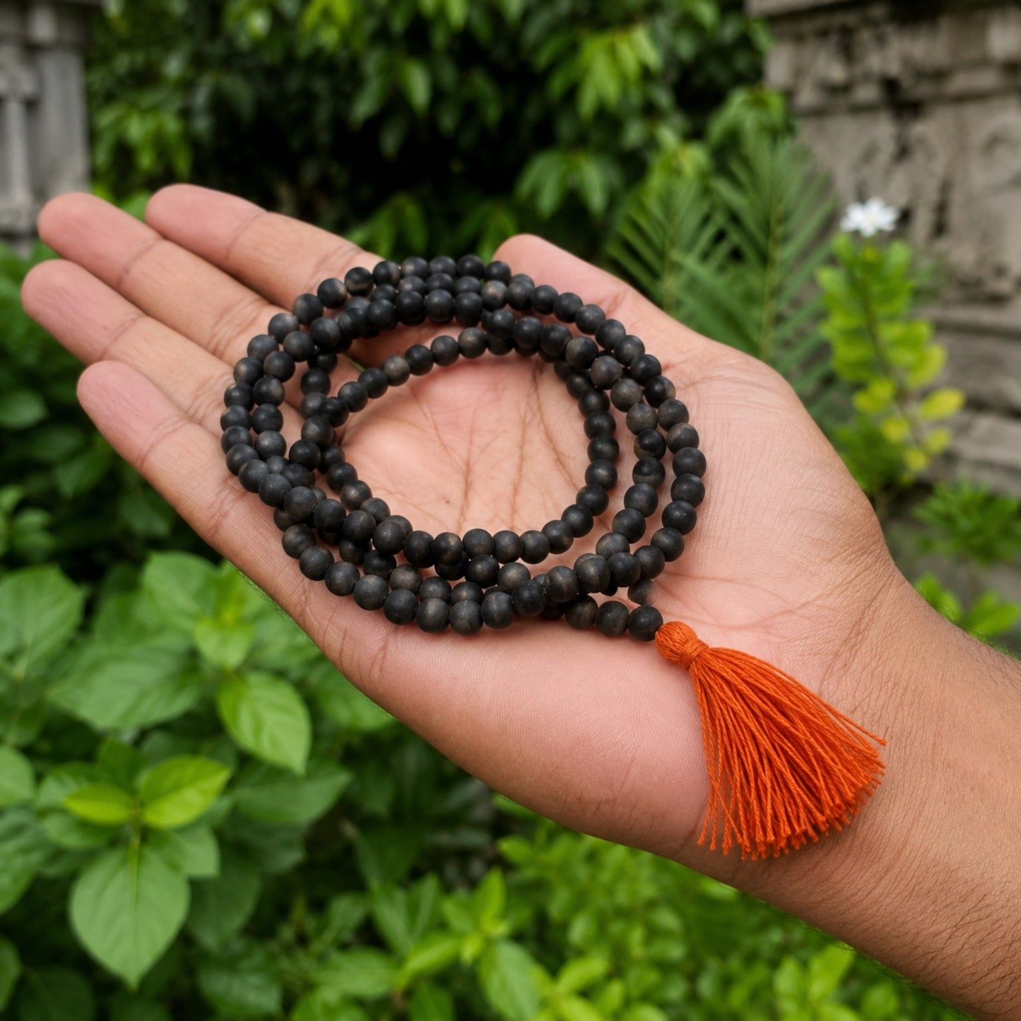 Classic Karungali Mala with orange tassel in hand